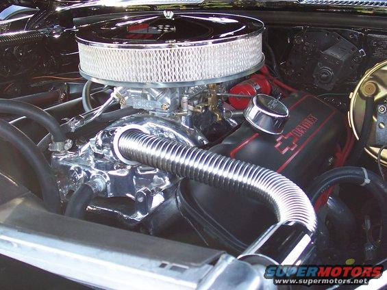 Engine bay showing chrome air cleaner, carburetor, and black Chevrolet valve covers with red lettering