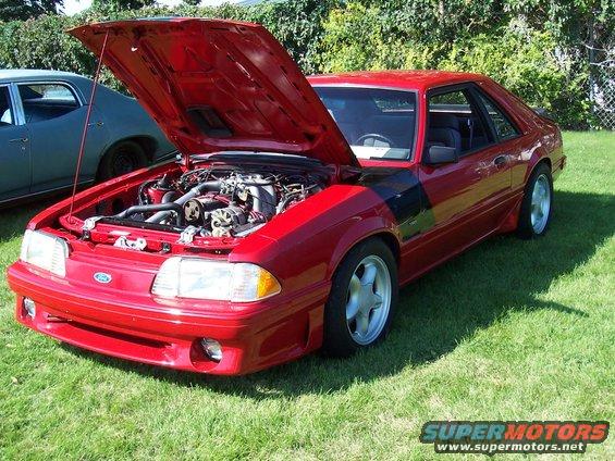 Red coupe with hood open, showing engine. Five-star wheels