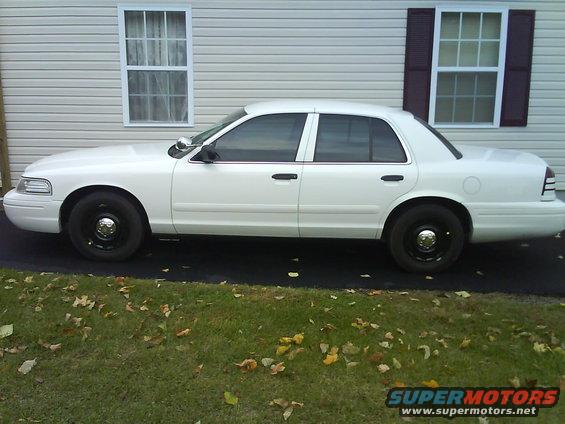 White 2003 Ford Crown Victoria parked on asphalt in front of a house