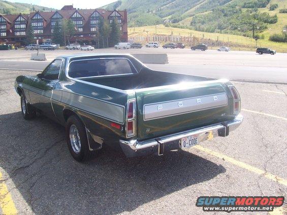 Green 1972 Ford Ranchero GT parked in a lot with a hotel and mountains in the background