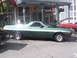 1972 Ford Ranchero - A green 1972 Ford Ranchero with a white stripe is parked on a street with its hood open.