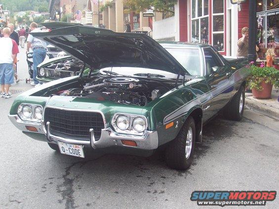 Green 1970s Ford Ranchero GT with hood open, parked on street