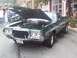 1972 Ford Ranchero - A green Ford Ranchero GT is parked on the street with its hood open, revealing the engine.