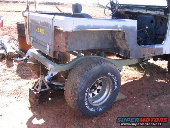 Jeep CJ body on jack stands, rear section visible. Some rust and body damage