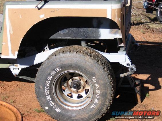 Jeep fender covered in cardboard, with a radial tire on a steel wheel