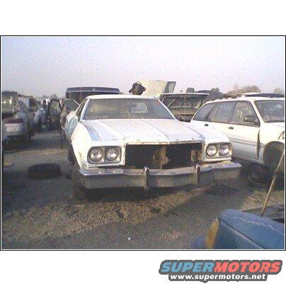 White 1977 Ford Ranchero in a junkyard, front view, missing grille and headlights