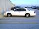 2003 Ford Crown Victoria - Side profile of a white 2003 Ford Crown Victoria parked in a lot with other vehicles.