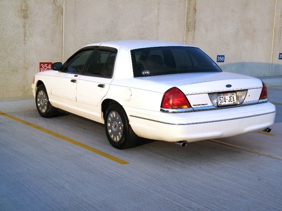 White sedan parked in a lot, rear view. License plate is 574-JEA