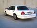 2003 Ford Crown Victoria - A white sedan is parked in a lot, showing its rear profile and license plate.
