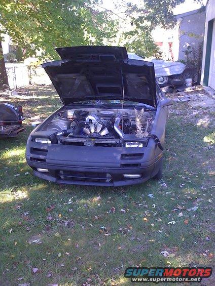 1991 Mazda RX-7 front view, hood open, showing engine and a cat sitting on the engine bay