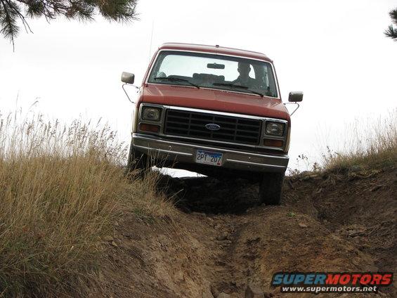 Red Ford truck on a dirt path, front view. License plate 2PT 207