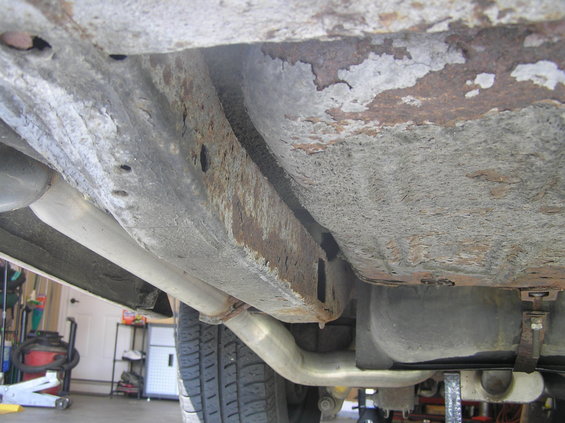 pb100011.jpg Rear driver's side framerail. In the foreground is the pan of the trunk which has surface rust. Just past the pan of the trunk is the gasoline tank. The tank is a replacement and is wet in this picture. The wetness is gas from a brittle gas line that I replaced just after taking this photo.