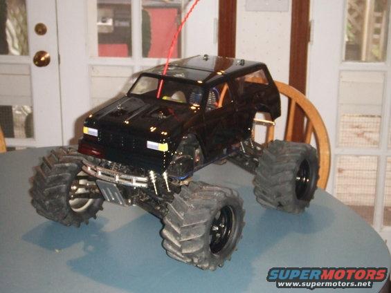 Black remote control monster truck with large tires sitting on a table