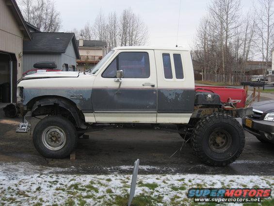 1990 Ford F-250 extended cab truck with large off-road tires, lifted suspension, and custom rear end