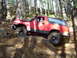 1989 Ford Bronco - A red 1989 Ford Bronco navigates a rocky trail in a forest setting.