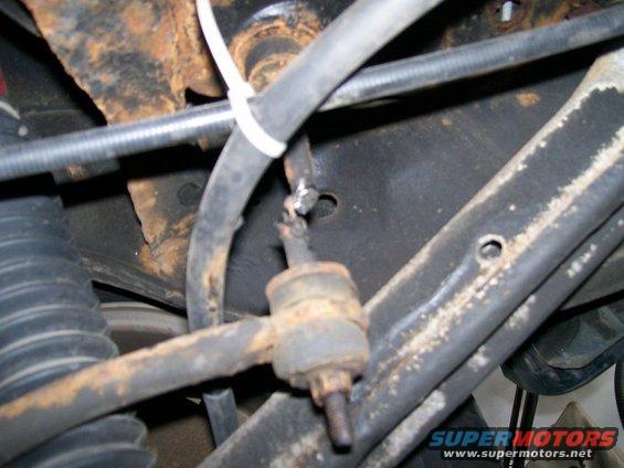 Close-up of rusty suspension parts, including a sway bar link and hoses, on a vehicle