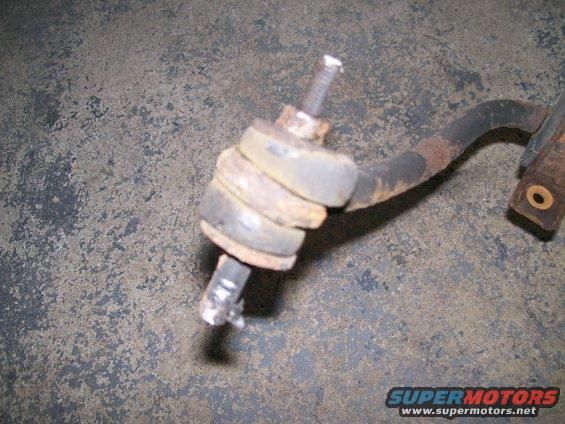 Rusty sway bar end link with rubber bushings and a bolt, on a concrete surface