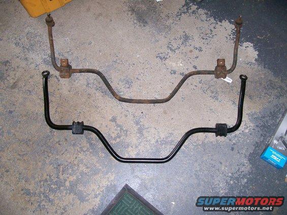 Rusty sway bar above a new black sway bar with rubber bushings