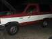 1989 Ford Bronco II - The two-tone red and white Ford Bronco II is parked outside with its hood up, revealing the engine compartment.