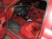 1989 Ford Bronco II - The interior of a red Ford Bronco II shows plaid seats and a dashboard with a steering wheel and gauges.