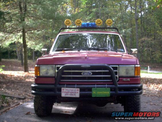 Red 1989 Ford Bronco front view with smiley face lights and bull bar