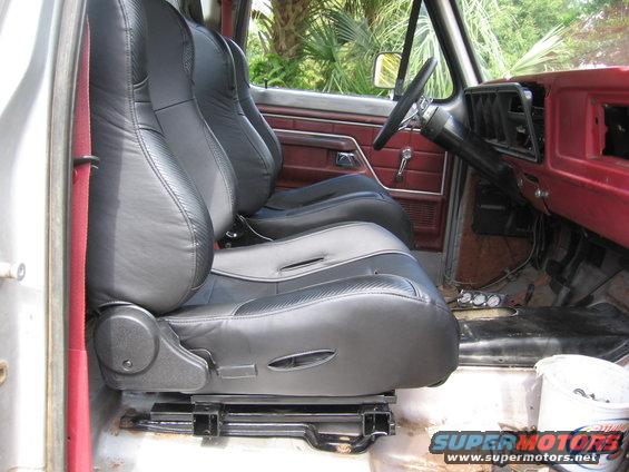 Truck interior with black aftermarket bucket seats and red door panels. Visible dashboard and steering wheel