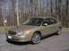 2001 Ford Taurus - A gold sedan with custom wheels is parked outdoors in front of a wooded area.