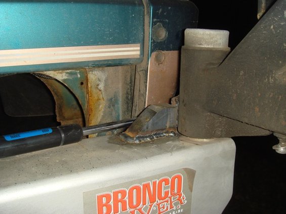 1996 Ford Bronco bumper stop with visible "BRONCO" text on a sticker, showing welded metal and teal bodywork