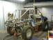 1994 Jeep YJ - This custom off-road vehicle is undergoing construction, a prominent roll cage and large tires, with its body stripped down.