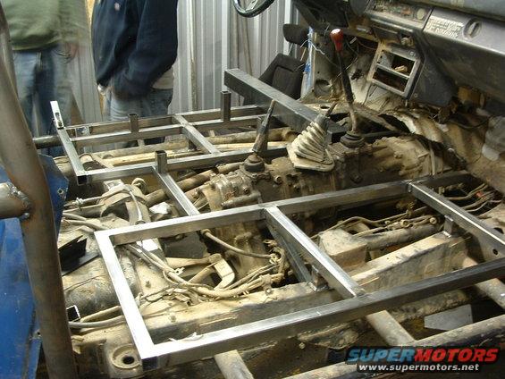Interior of a vehicle with a metal frame being welded in place over the transmission and floor