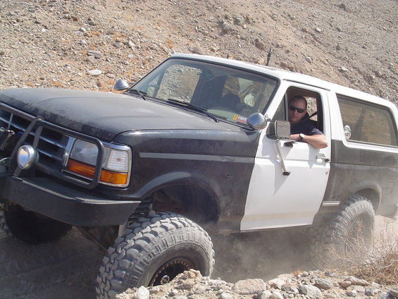 Ford Bronco with lifted suspension and off-road tires driving on a rocky trail