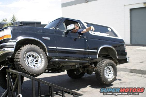 Black Ford Bronco with lifted suspension on ramps, driver's side visible