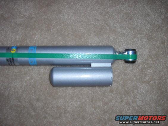 Silver shock absorber with green band and blue markings. Another silver cylinder is attached
