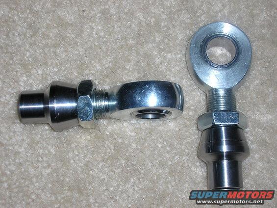 Two metal rod ends with hex nuts on threaded shafts, resting on a carpeted surface