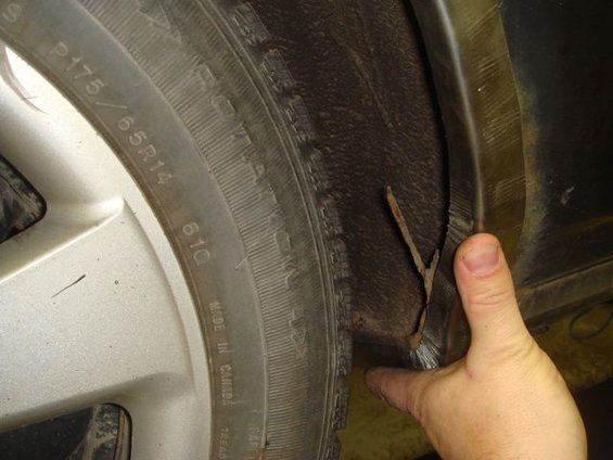 Close-up of a tire and wheel well showing debris stuck in the fender liner