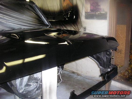 Black vehicle hood and fender being painted