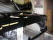 1987 Ford Bronco - A black vehicle hood and fender are shown during a painting process in a workshop.