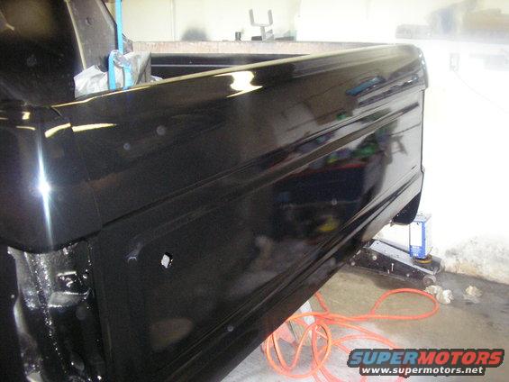 black pickup truck bed, jacked up for repair
