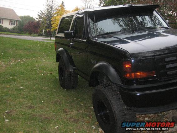 Black Ford Bronco with lifted suspension and aftermarket fender flares parked on a grassy lawn