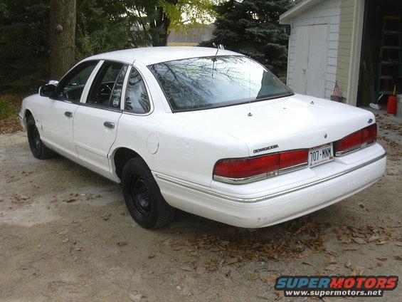 1997 Ford Crown Victoria, rear 3/4 view, white with black steel wheels