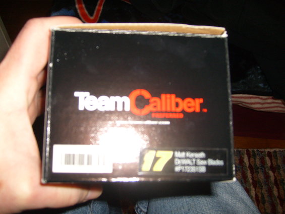 Black cardboard box with 'Team Caliber' logo and barcode, held by a hand