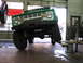 1975 Ford Bronco - Green 1975 Ford Bronco is being serviced on a lift in a garage.