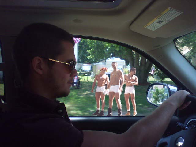 Interior view of car with three men in white briefs visible through the windshield