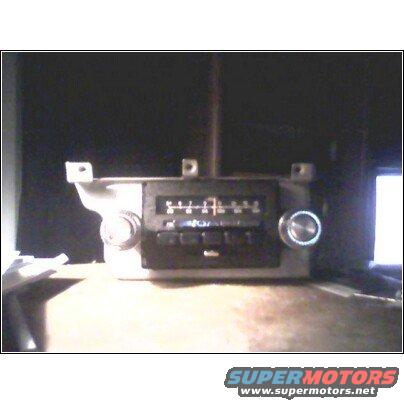Car radio with knobs and push buttons, set against a dark background