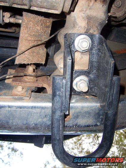 Close-up of a vehicle's undercarriage showing a tow hitch attached to the frame. Some rust is visible on other components