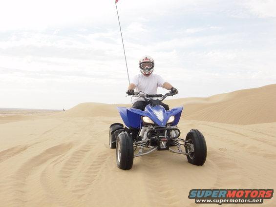 Blue ATV with rider in sand dunes, front view