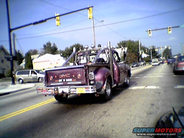 Customized GMC pickup truck with "OFF R DONE" on tailgate, driving on a sunny day
