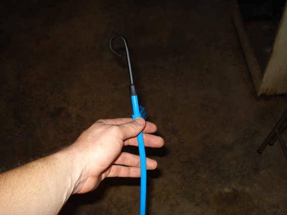Hand holding a blue and black engine part with a curved hook