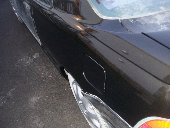 Black car's rear quarter panel with fuel door and chrome trim