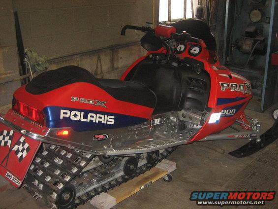 Red and blue Polaris snowmobile with 'PROX' and 'POLARIS' graphics. Has a checkered flag sticker on the rear